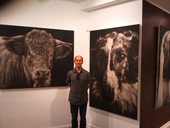 Piotr Wojcik et ses peintures lors d'une exposition.